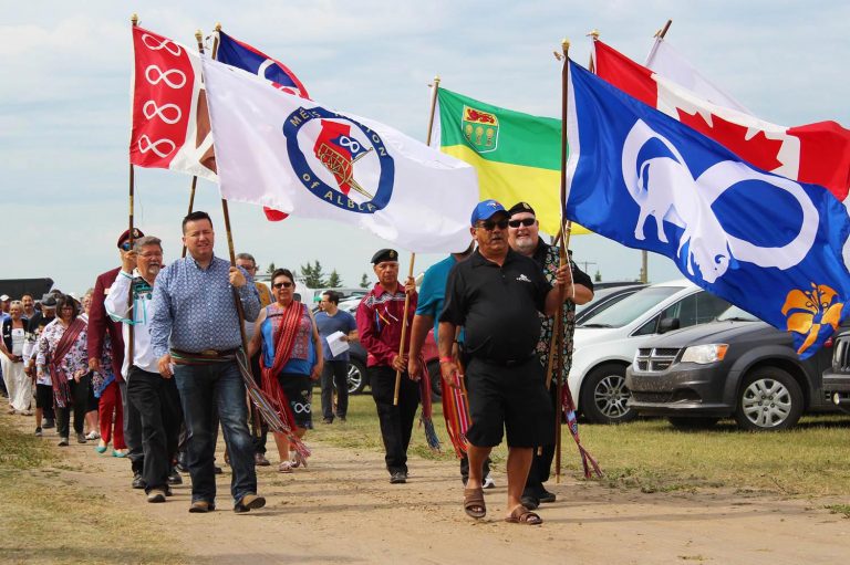 Procession walking with flags at Back to Batoche 2018